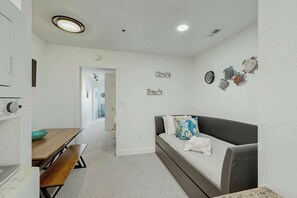 A modern living room with a sofa, a dining table, and a kitchen area with a microwave. - La Mirage Unit 402 Condo (Myrtle Beach)