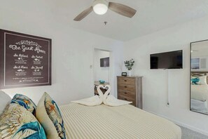 A hotel room with a bed, a ceiling fan, a flat-screen TV, a dresser, and a wall-mounted mirror. - La Mirage Unit 402 Condo (Myrtle Beach)