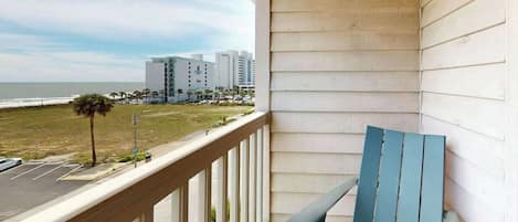 A balcony with a view of the beach and buildings.