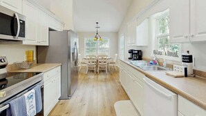 Eine Küche mit weißen Schränken, einem Edelstahl-Kühlschrank, einer Mikrowelle und einem Essbereich mit Tisch und Stühlen.