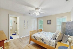 A bedroom with a bed, a ceiling fan, a bedside table, and a window with blinds. - Pawleys Beach Retreat (Pawleys Island)