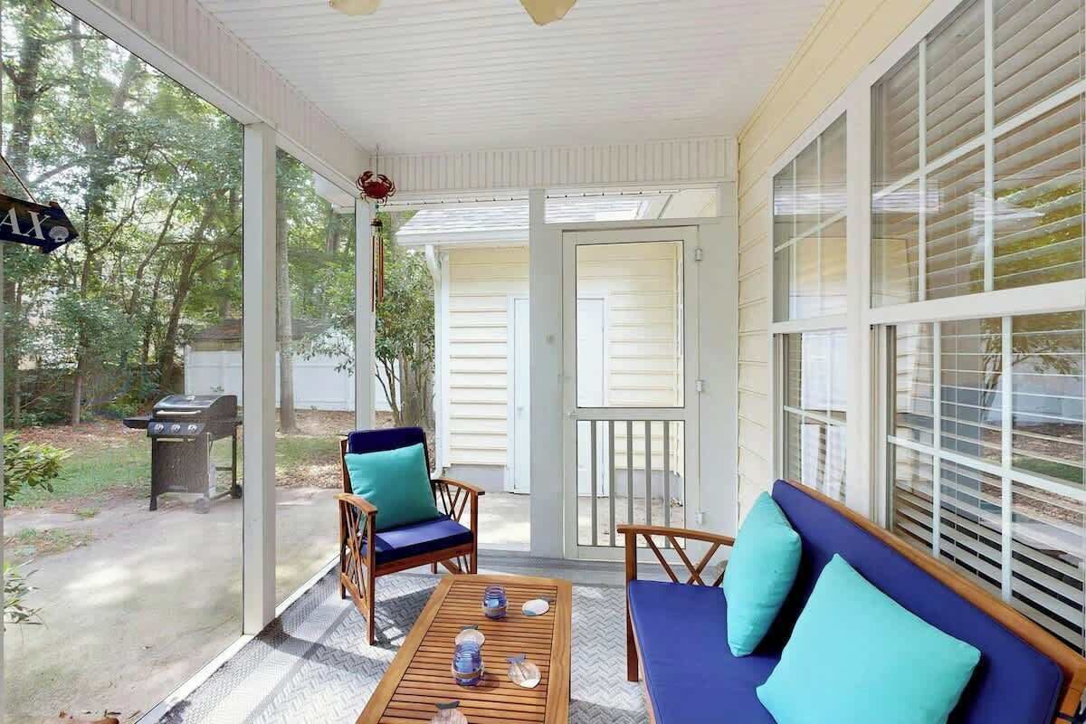 A covered porch with a wooden table, two chairs, and a sofa.