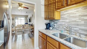 A kitchen with wooden cabinets, a granite countertop, and a backsplash. - Whalecome Inn Retreat (Myrtle Beach)