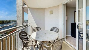 A balcony with a round table and chairs, overlooking a marina with boats. - Yacht Club Villas 2-702 (North Myrtle Beach)