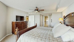 A bedroom with a bed, a dresser, a ceiling fan, and a television. - Yacht Club Villas 2-702 (North Myrtle Beach)
