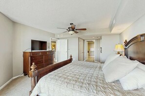 Ein Schlafzimmer mit einem Bett, einem Schminktisch, einem Deckenventilator und einem Fernseher.