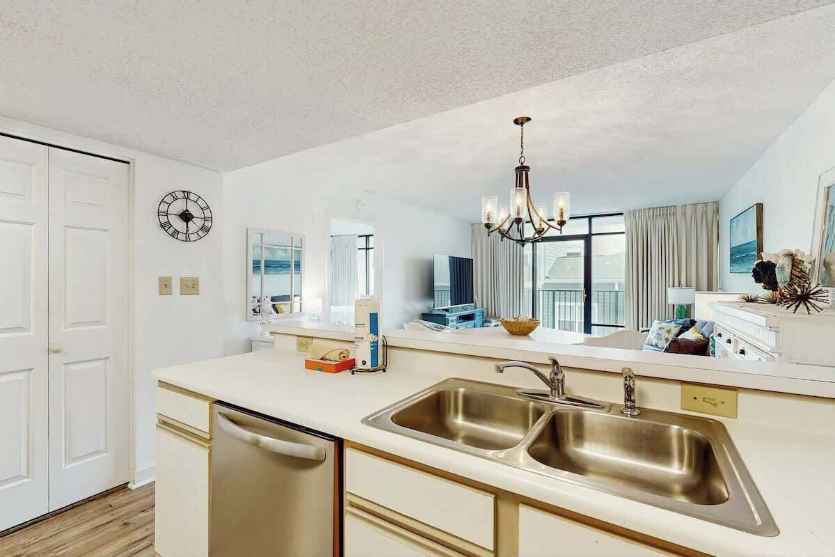 A modern kitchen with a double sink, a dishwasher, and a chandelier.