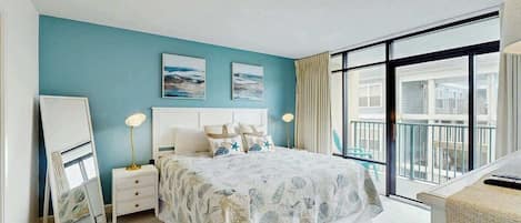 Une chambre avec un grand lit, une table de chevet, un miroir et une vue sur le balcon extérieur.