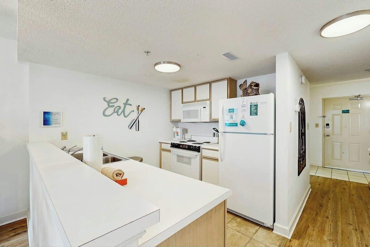 A modern kitchen with white cabinetry, a built-in microwave, and a refrigerator.