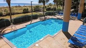 Ein Pool mit Blick auf den Ozean, umgeben von Palmen und Liegestühlen.
