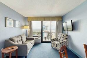 A hotel room with a sofa, armchair, TV, and a balcony with a view. - The Patricia Grand 1804 (Myrtle Beach)
