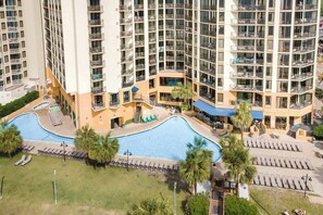 A high-rise building with multiple balconies, a swimming pool, and sun loungers. - The Patricia Grand 1804 (Myrtle Beach)