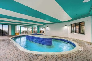 Ein Schwimmbecken mit einer gefliesten Kante, einem Backsteinboden und einer Decke mit türkis-weißen Paneelen.