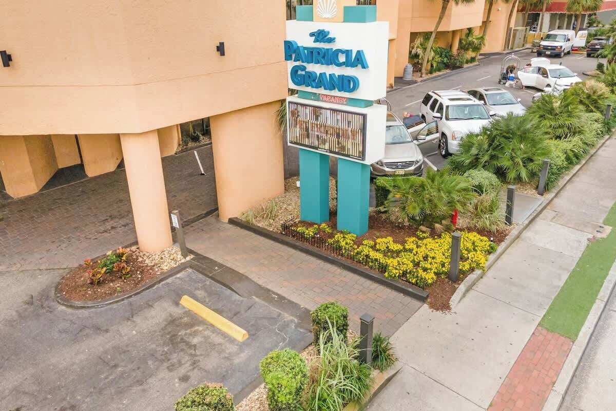 A hotel sign with a parking lot and a few cars.