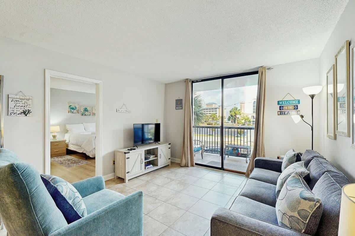 Una sala moderna con un sofá, un sillón y un televisor sobre un mueble.