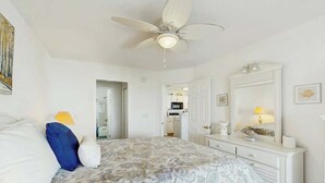 A bedroom with a bed, a ceiling fan, a dresser, and a mirror. - Carolina Yacht Landing E-13 (Little River)