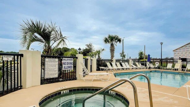 A swimming pool area with lounge chairs and palm trees. - Carolina Yacht Landing E-13 (Little River)