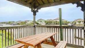 A wooden deck with a picnic table and benches overlooking a marina with boats and houses in the background. - Carolina Yacht Landing E-13 (Little River)