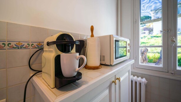 Eine Küche mit Kaffeemaschine, Mikrowelle und einem Fenster mit Blick auf Grünflächen.