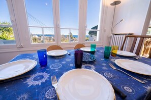 A dining table set for four with plates, cutlery, and colorful glasses, overlooking a scenic view. - L’Ousteau Provençal – Family Home with Sea View (Vallauris)