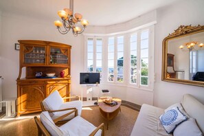 A room with a wooden cabinet, a television, a sofa, and a large mirror. - L’Ousteau Provençal – Family Home with Sea View (Vallauris)