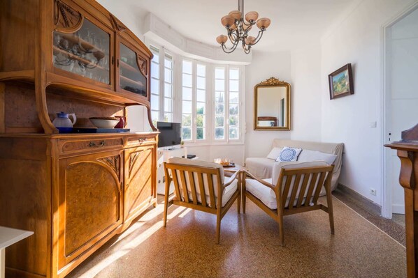 A room with a wooden cabinet, a sofa, a table, and a mirror.