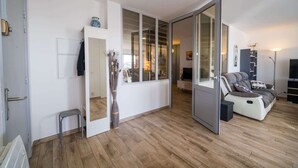 Ein modernes Wohnzimmer mit einer Couch, einem Couchtisch und einem Fernseher. Eine Schiebetür führt in einen weiteren Raum.