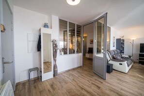 A modern living room with a sofa, a coffee table, and a TV. There is a sliding door leading to another room. - Large apartment 5 mn walking to the beach, parking (Antibes)