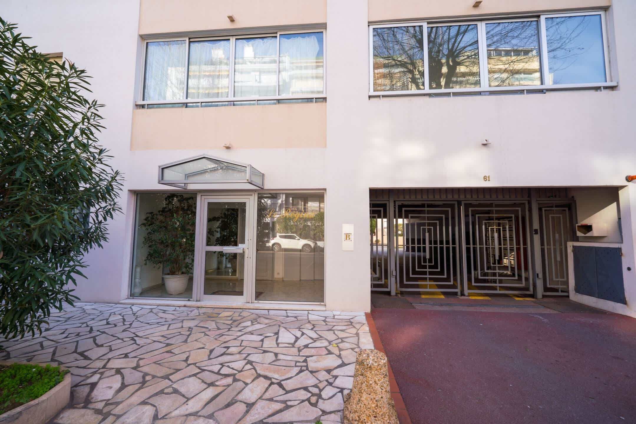Un edificio con entrada de losas de piedra, puerta de cristal y reja metálica.