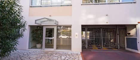 Un edificio con entrada de losas de piedra, puerta de cristal y reja metálica.