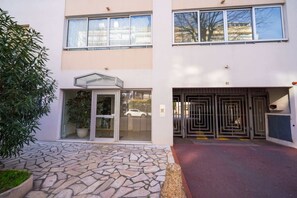 A building with a stone-tiled entrance, a glass door, and a metal gate. - Large apartment 5 mn walking to the beach, parking (Antibes)