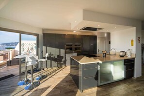 A modern kitchen with a large island, stainless steel appliances, and a view of the city. - Large apartment 5 mn walking to the beach, parking (Antibes)