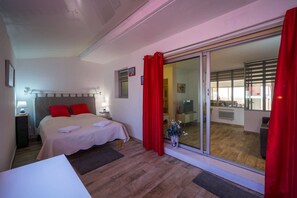 Een hotelkamer met een bed, nachtkastjes, een raam en een schuifglazen deur naar een balkon.