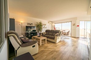 A living room with a sofa, armchair, coffee table, TV, and a potted plant. - Large apartment 5 mn walking to the beach, parking (Antibes)