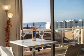 Ein Tisch mit einer Flasche und zwei Gläsern, mit Blick auf eine Küstenstadt.