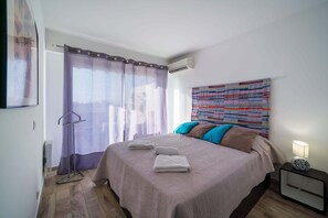 Ein Schlafzimmer mit einem Bett, einem Nachttisch, einer Lampe und einem Fenster mit Vorhängen.