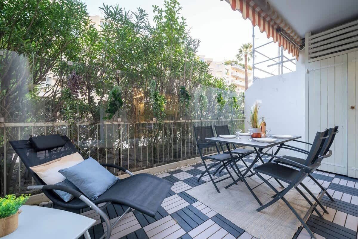 A balcony with a table, chairs, and a lounge chair.