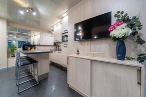 A modern kitchen with a flat-screen TV, a bar area, and a dining space. - Azure sky, center, beach, terrace, Croisette (Cannes)