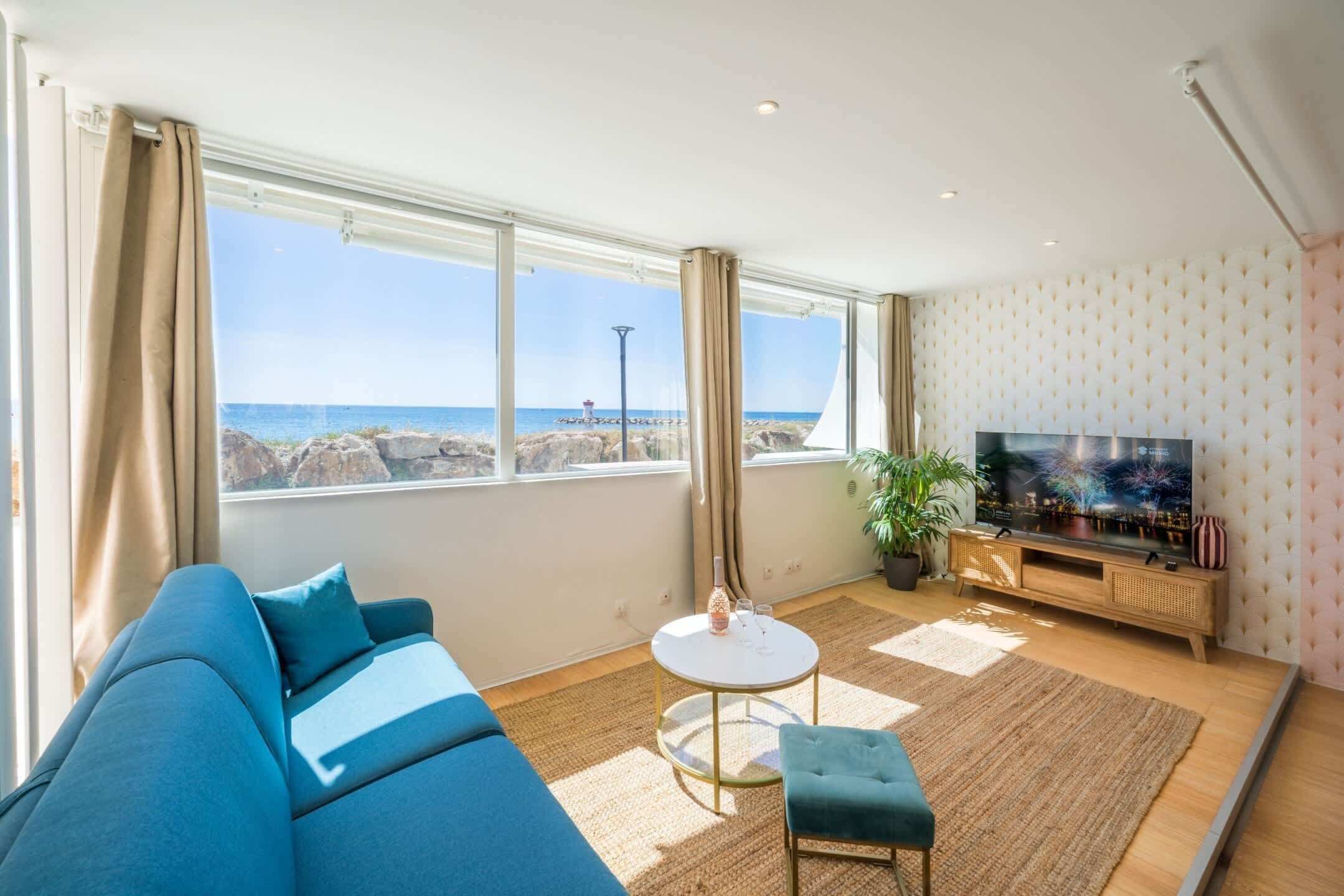 Een moderne woonkamer met een groot raam, een bank, een klein rond tafeltje, een televisie en een potplant.