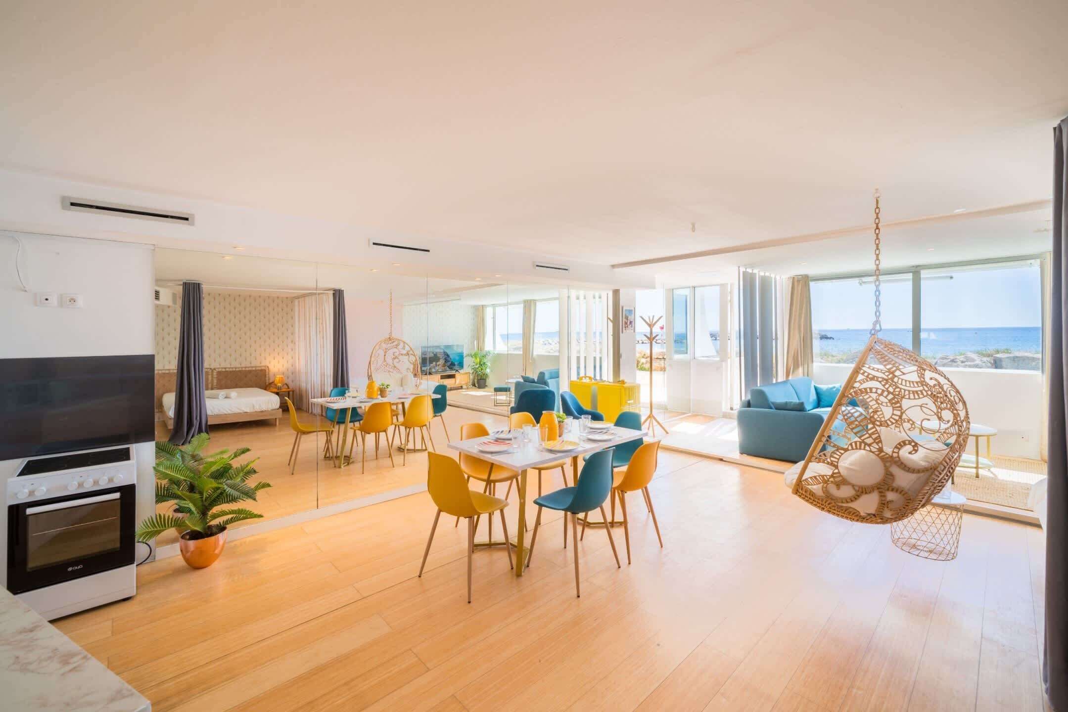 Ein modernes Hotelzimmer mit Essbereich, einer Küche und einem Balkon mit Meerblick.