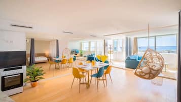 Ein modernes Hotelzimmer mit Essbereich, einer Küche und einem Balkon mit Meerblick.