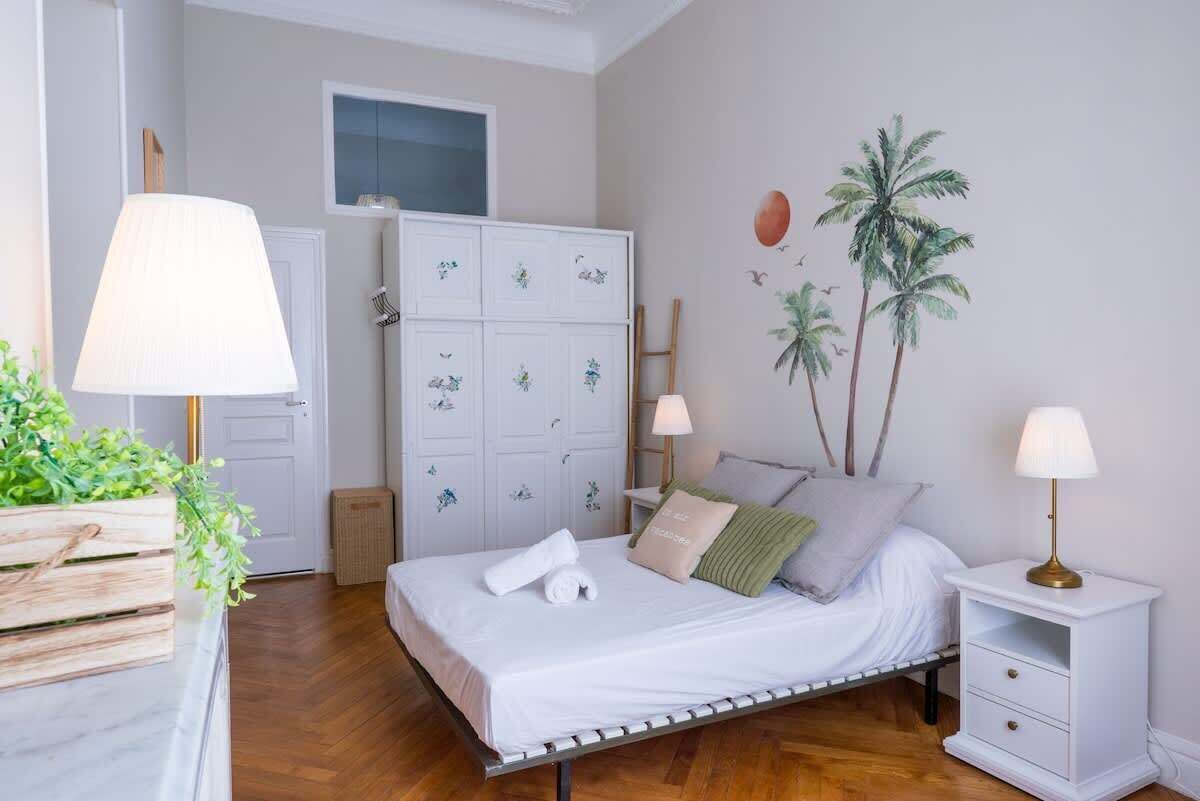 Ein Schlafzimmer mit Bett, Nachttischen, einem Kleiderschrank und einer Wandmalerei.