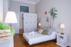 A bedroom with a bed, bedside tables, a wardrobe, and a wall mural. - Parthenopi suite – proche palais et ville (Cannes)