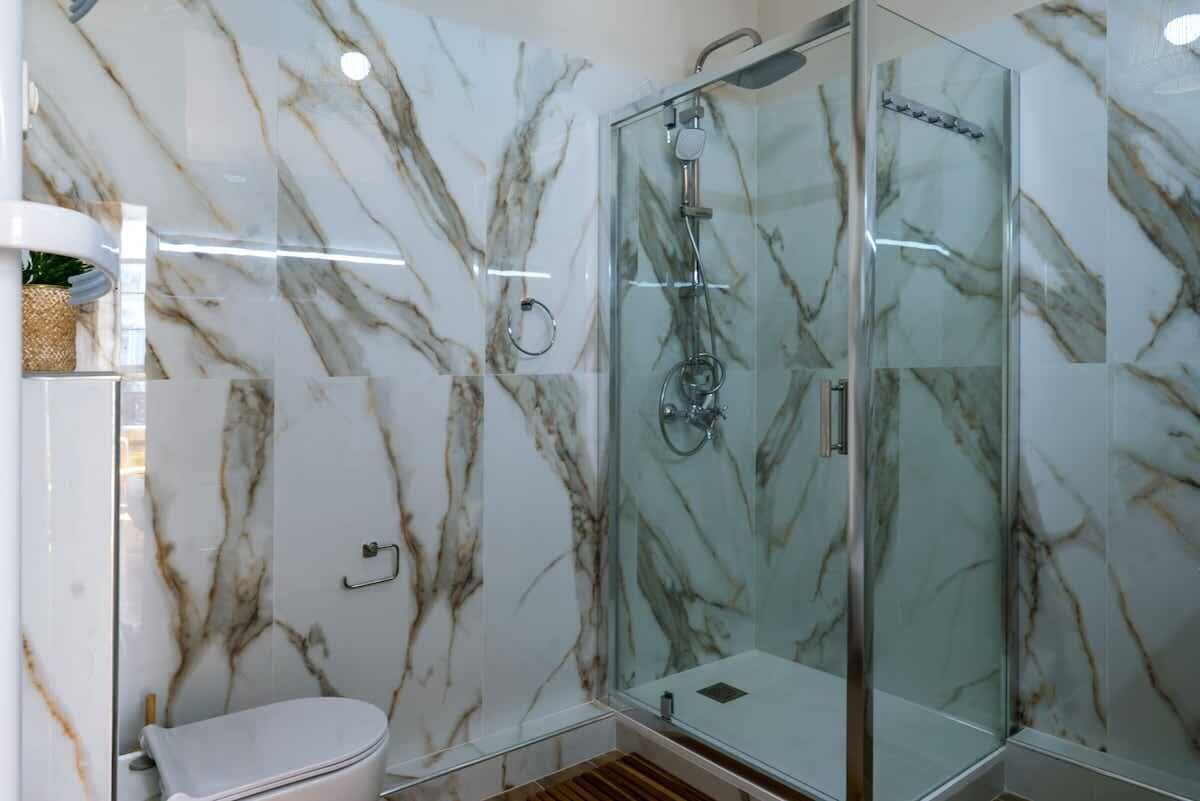 Un bagno con doccia vetrata, un water e pareti in marmo.
