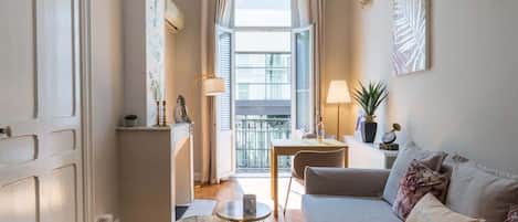 A cozy living room with a sofa, a dining table, and a balcony view.