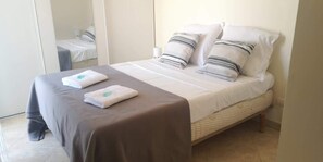 A neatly made bed with a brown bedspread and two pillows, a bedside table with a lamp, and a mirror on the wall. - L’Escapade Juan Flore, relaxation, family pool (Antibes)