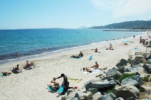 A beach with people sunbathing and swimming, a rocky shoreline, and a clear view of the sea. - L’Escapade Juan Flore, relaxation, family pool (Antibes)