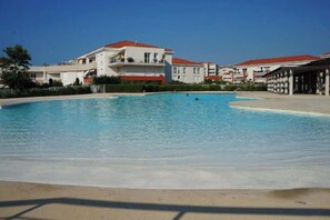A swimming pool with a clear blue water surface, surrounded by buildings with red roofs and balconies. - L’Escapade Juan Flore, relaxation, family pool (Antibes)