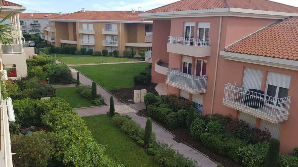 Un edificio residencial con varios balcones, un césped cuidado y un cielo despejado.