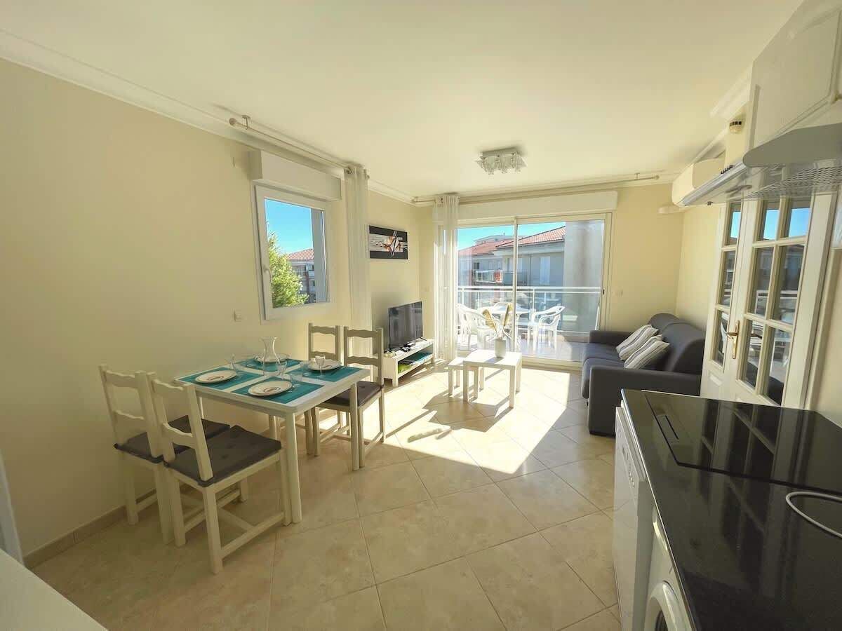 A spacious living area with a dining table, chairs, a sofa, and a kitchen area.